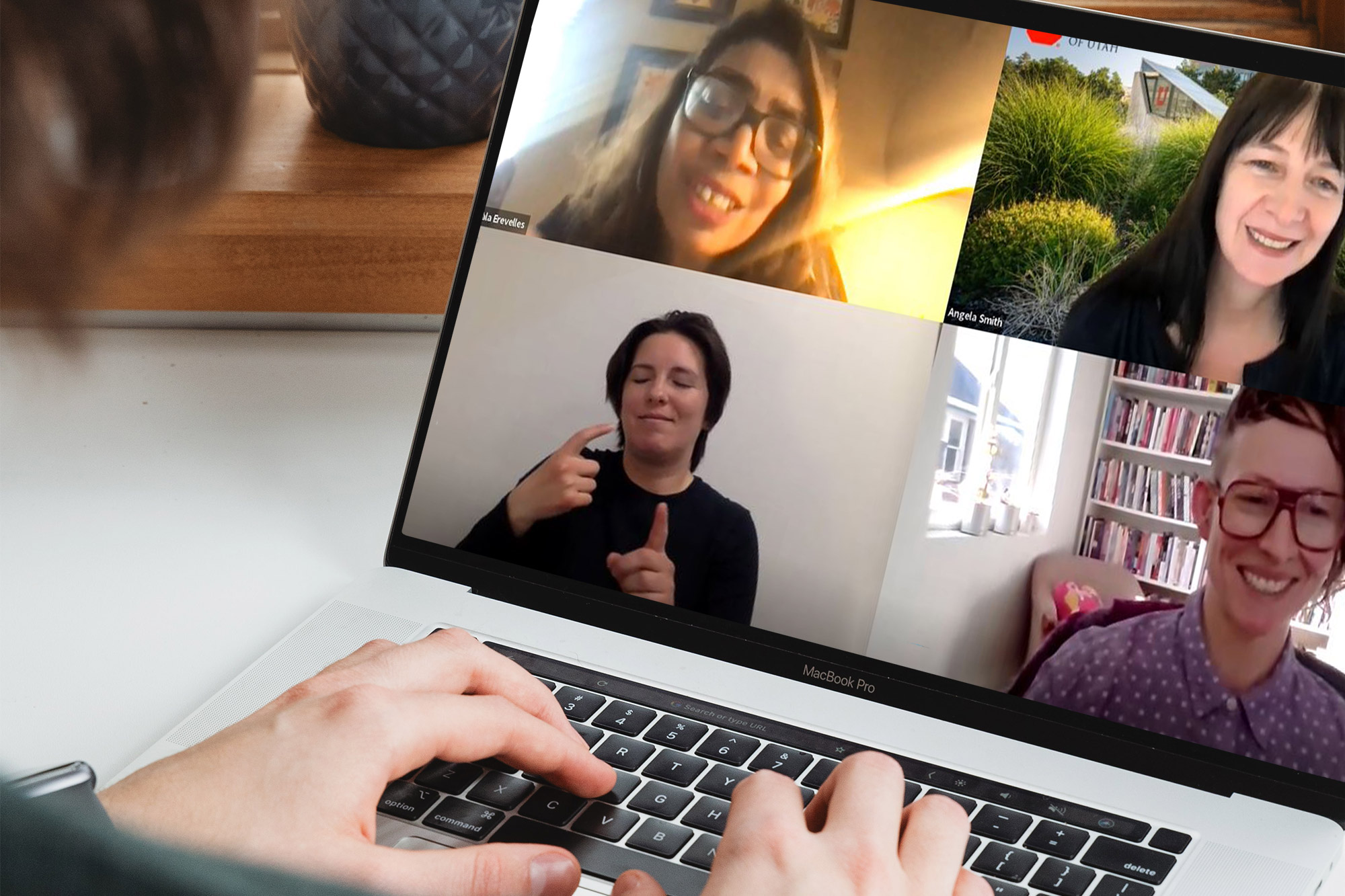 Nirmala Erevelles and a sign-language interpreter appear on a laptop screen, with two hands resting on the keyboard