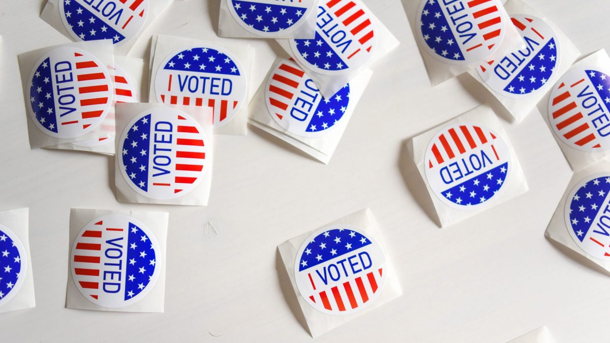 a top view of a white table covered in 'I Voted' stickers with the American flag